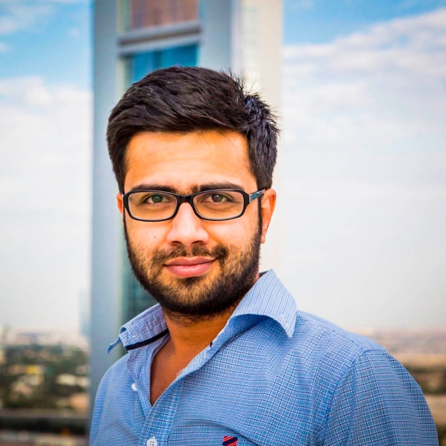 Portrait of Akbar Noorani wearing glasses and a blue checked shirt.