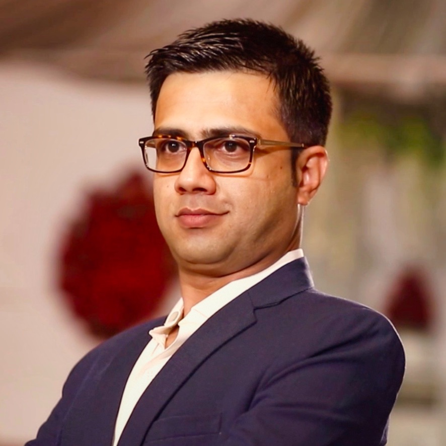 Portrait of Akbar Noorani wearing glasses and a navy suit.